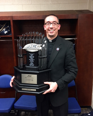 Father Pete, chaplain of the Notre Dame men's basketball team, holding the ACC trophy